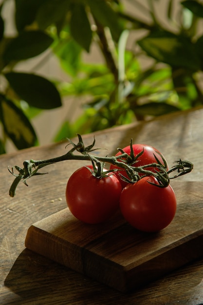 A branch of red tomatoes lies on a wooden board