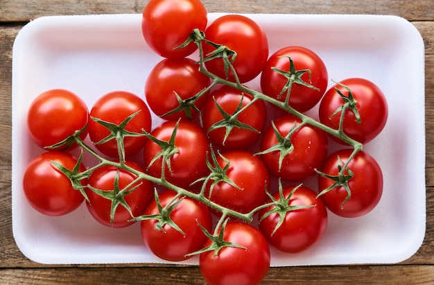 Branch of ripe cherry tomatoes in plastic packaging