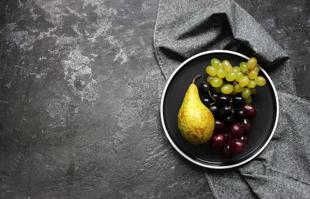 Branch of ripe green grape on plate with water drops Juicy grapes on wooden background closeup Grapes on dark kitchen table with copy space