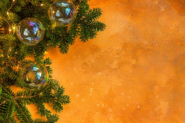 Photo a branch of spruce with christmas toys in the form of soap bubbles and a garland on a yellow . festive mood. flat lay.top view. copyspace.