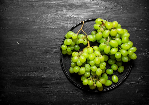 Branch of white grapes on a plate.