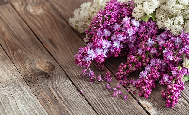 Branches of blooming fresh lilacs on a dark wooden table.