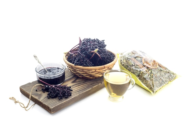 Branches of elderberry tea and jam from it closeup on a white background