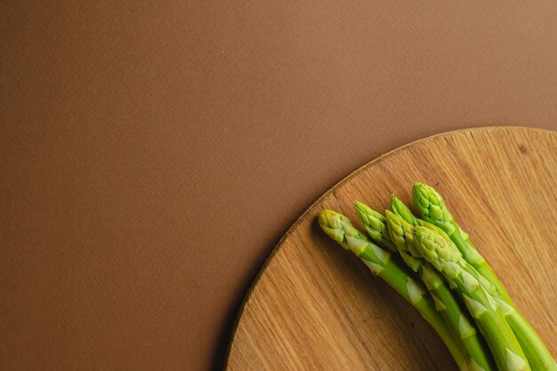 Branches of fresh green asparagus on a wooden board brown\
background top view basic trend concept with copy space