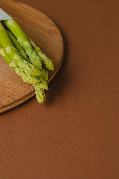 Branches of fresh green asparagus on a wooden board brown background top view Basic trend concept with copy space