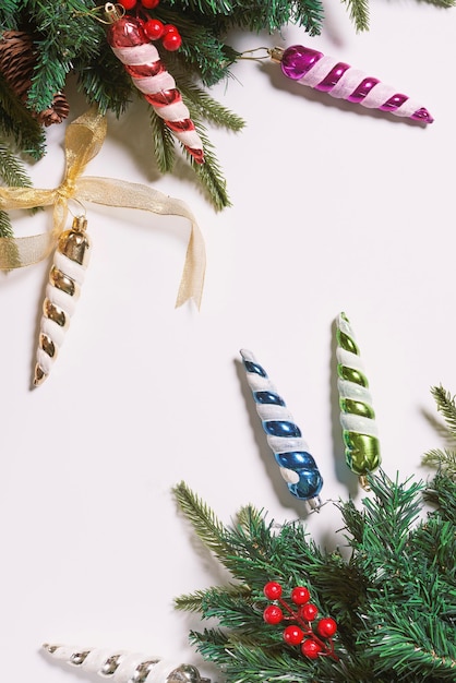 Branches of spruce tree with pine cones and christmas toy decorations on white