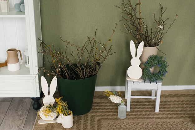 Branches in vases wooden figurines of a rabbit and a wreath in the decor of the house for the Easter holiday