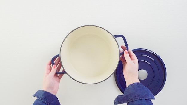 Brand new enameled cast iron covered dutch oven on a white background.