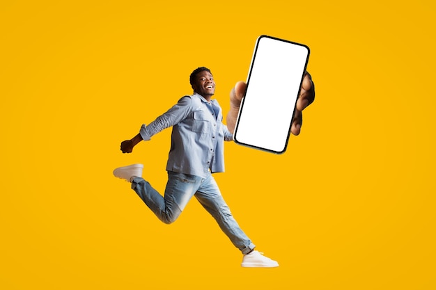 점프하는 남자 손에 빈 화면이 있는 새로운 스마트폰