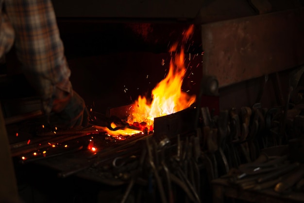 Brand van smid in de werkplaats van de smid Smid aan het werk geraakt met een hamer door een heet metaal op het aambeeld