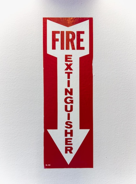 brandblusser en bord tegen de witte muur veiligheidsconcept in huis of op de werkplek
