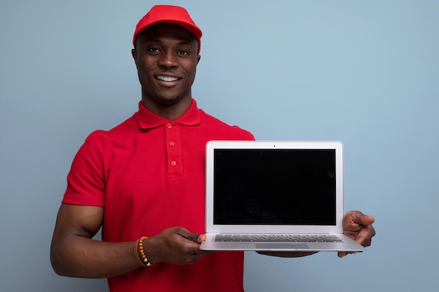 노트북 화면에 광고를 표시하는 빨간 티셔츠와 모자를 쓴 브랜드 의류 개념 미국 남자