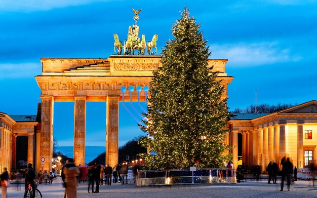 Brandenburger Tor gebouw in Berlijn, Duitsland. 's Nachts verlicht. Kerstboom op straat in de winter. Geschiedenis en toerisme voor mensen, reizigers en toeristen. Blauwe lucht in de avond