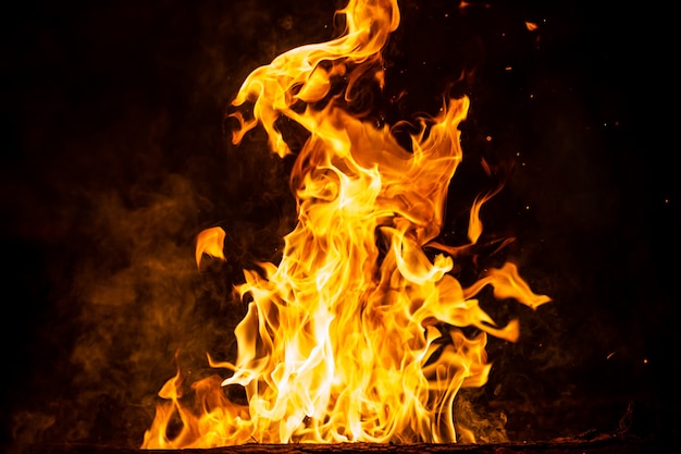 Brandend hout met vuursporen, vlammen en rook. vreemde rare vreemde elementaire vurige figuren op zwarte achtergrond. steenkool en as. abstracte vormen 's nachts. vreugdevuur buiten op de natuur. sterkte van element