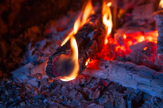 Brandende houtblokken in de open haard close-up, op de achtergrond verbrand brandhout