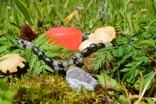 Brandende kaars een symbool van de maan een amulet liggend op het mos op een donkere natuurlijke achtergrond