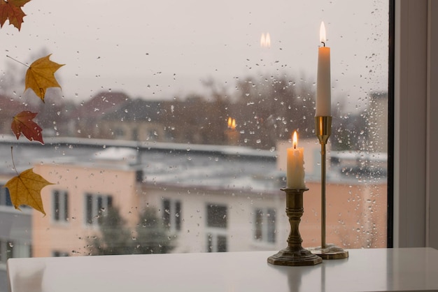 Brandende kaarsen op regenachtige ruit als achtergrond