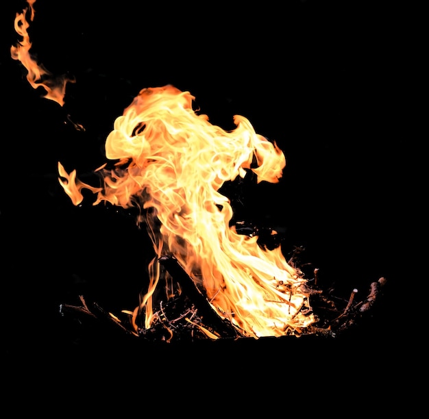 Brandhout branden met een sterke en hoge vlam op een zwarte achtergrond, vreugdevuur