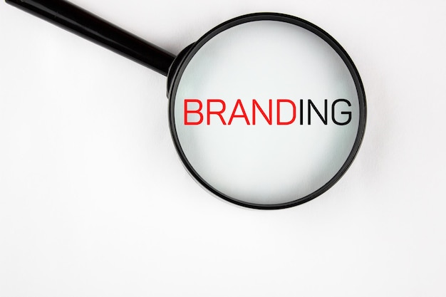 Foto branding business concetto parola branding attraverso una lente d'ingrandimento su un foglio bianco