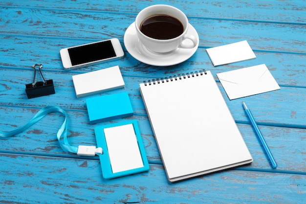 Branding stationery  on blue desk. Top view of paper, business card, pad, pens and coffee.