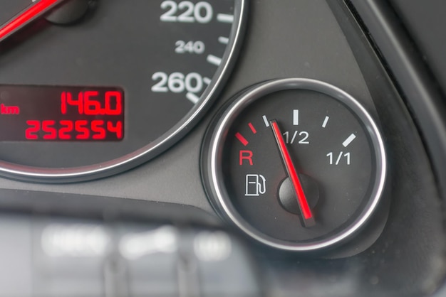Foto brandstofmeter met rode indicator op leeg niveau close-up auto dashboard benzinemeter