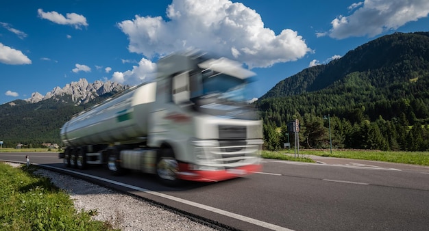 Brandstofvrachtwagen snelt onderaan de weg op de achtergrond de Alpen. Vrachtwagen auto in bewegingsonscherpte.