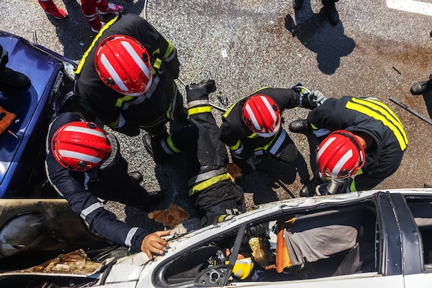 Brandweerlieden die de man uit de gecrashte auto proberen te bevrijden. er is een gecrashte auto bij auto-ongeluk.