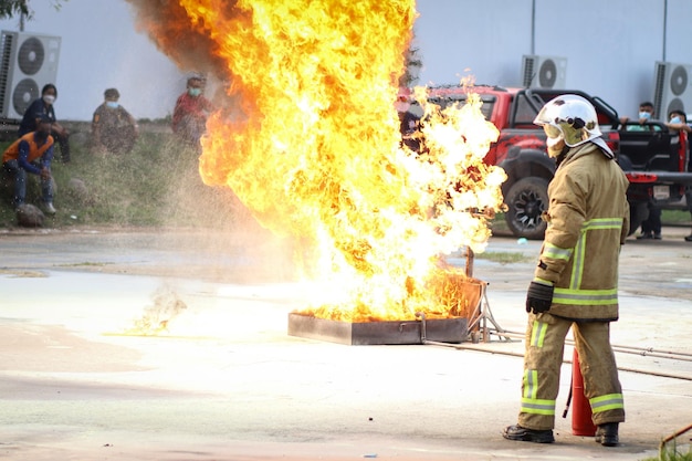 Brandweerlieden die Twirl watermist type brandblusser gebruiken om te vechten met de vuurvlam van olie om het vuur onder controle te houden om zich niet uit te spreiden Brandweerman en industrieel veiligheidsconcept