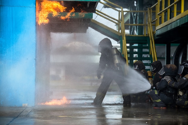 Brandweerlieden die water van slang gebruiken voor brandbestrijding bij firefight training van verzekeringsgroep