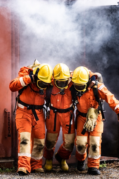 Brandweerlieden redden een collega uit een brandend gebouw met rook