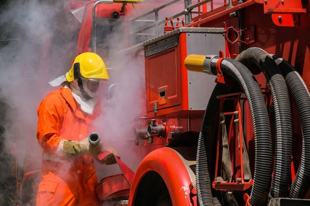 Brandweerlieden training, teamoefening om in noodsituaties met brand te bestrijden. een brandweerman maakt een slang vast aan het brandweervoertuig