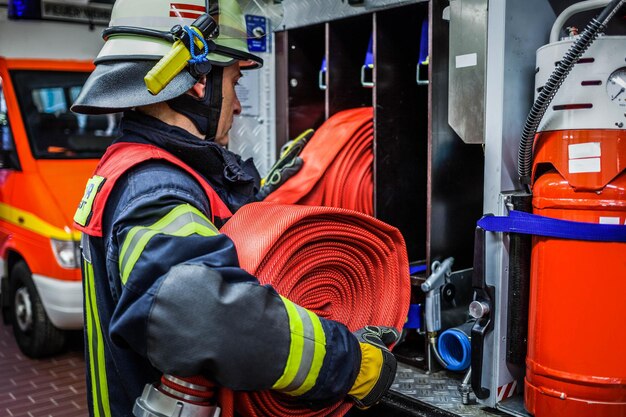 Foto brandweerman die de slang in het rek van een brandweerkazerne rangschikt