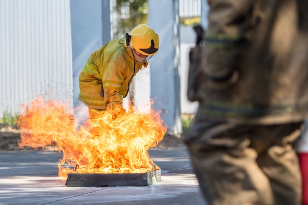 Foto brandweerman die gebruik een brandblusapparaat op een opleidingsbrandkraan met witte rook toont. arbo-concept.