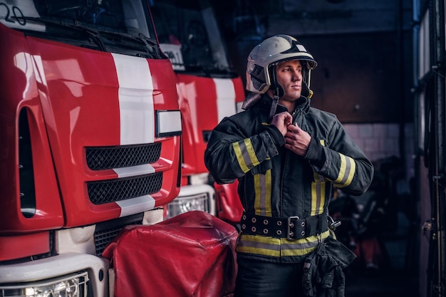 Brandweerman kleedt beschermende uniformen naast de brandweerwagen in de garage van een brandweer