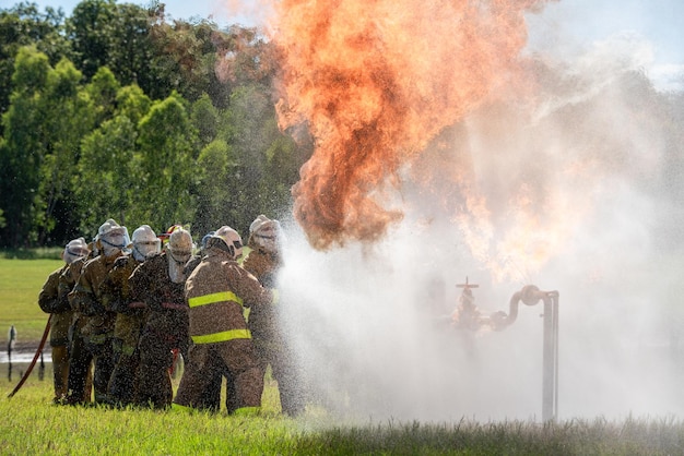 Brandweermannen en reddingstraining Brandweerman spuit water onder hoge druk op brand Brandende vlam achtergrond
