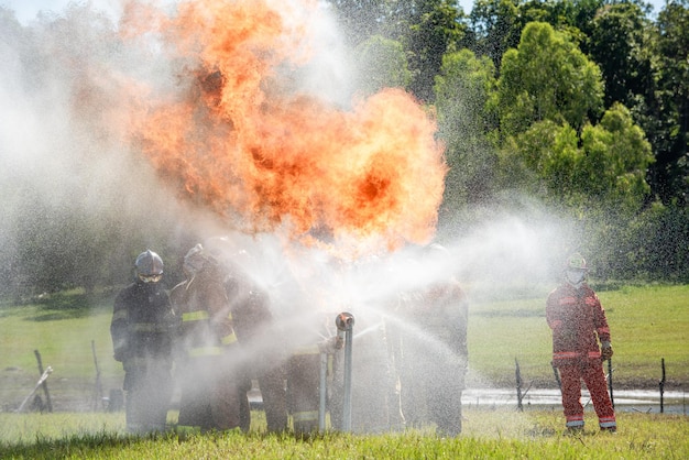 Brandweermannen en reddingstraining Brandweerman spuit water onder hoge druk op brand Brandende vlam achtergrond