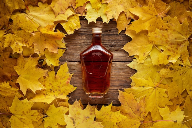 Photo brandy bottle on yellow maple leaves