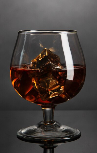 Photo brandy glass with ice on grey background