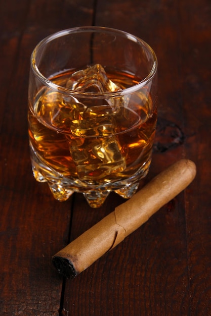 Brandy glass with ice on wooden background