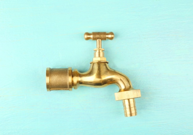 Brass faucet on color wooden background