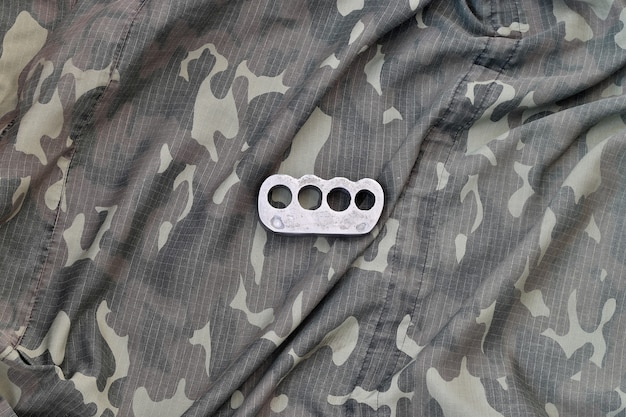 Brass knuckles on crumpled camouflage clothes