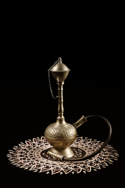 a brass lamp with a black background and a silver handle