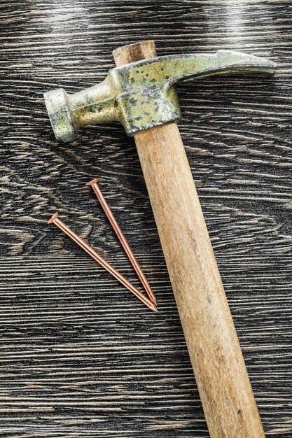 Photo brass nails claw hammer on wooden board