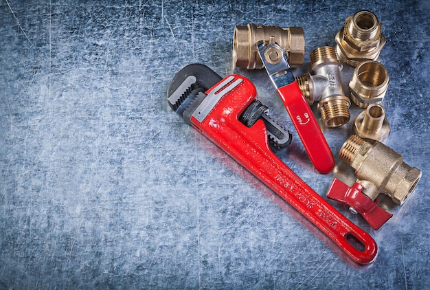 Brass pipe connectors monkey wrench on metallic background plumbing concept.