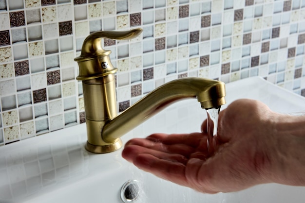 Brass single elbow lever mono mixer tap in bathroom hand is checking water temperature