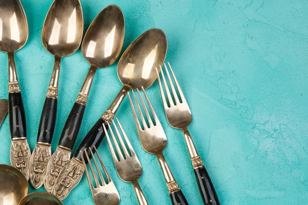 Brass spoons and forks on concrete background. 