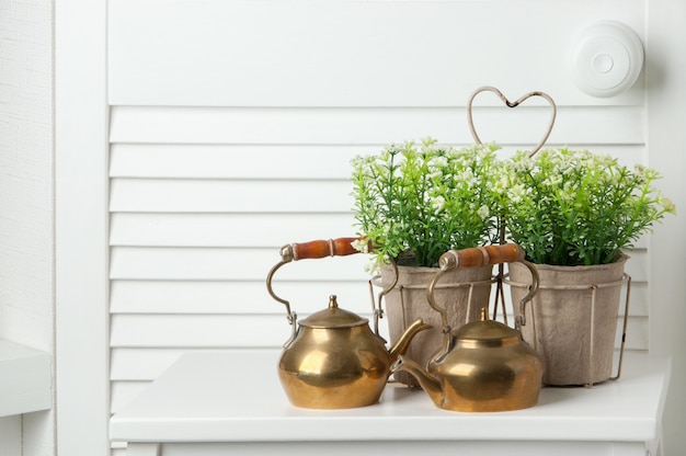 Brass teapots on white door