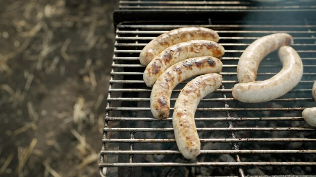 Bratwurst or hot dogs on grill with flames sausages are fried on a barbecue grill