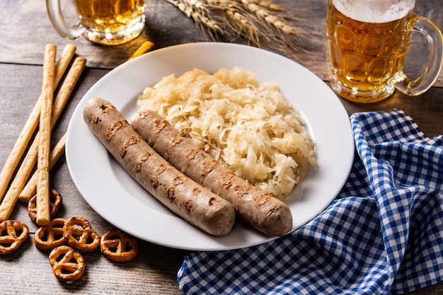 Колбаса Bratwurst, квашеная капуста, крендели и пиво на деревянном столе