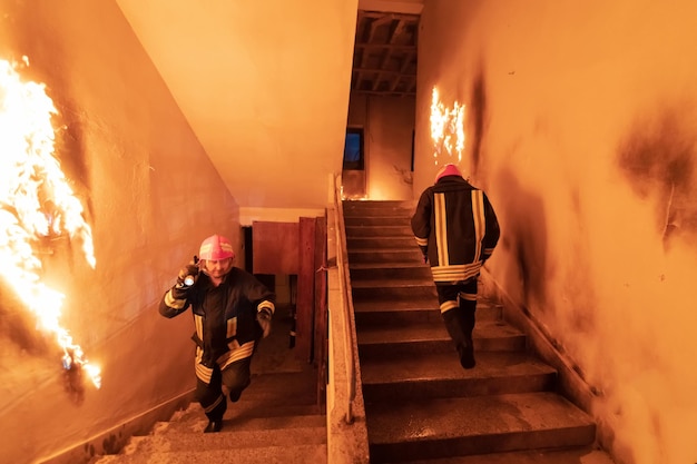 Brave Fireman going upstairs to save and rescue people in a Burning Building. Open fire and flame. Low light hi is selective focus stock photo.